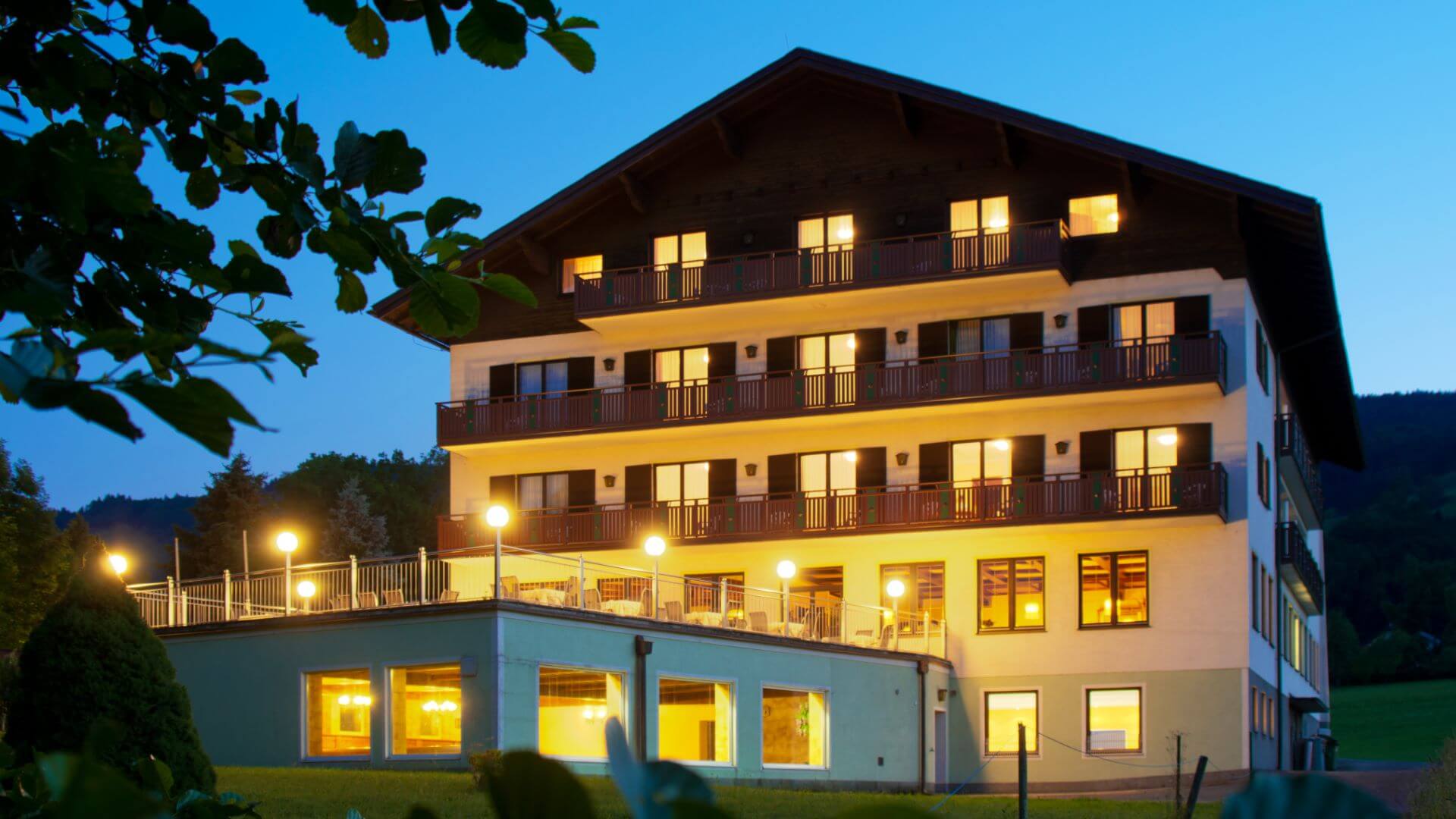 Mehrstöckiges Gebäude bei Nacht, beleuchtete Fenster, Balkone.